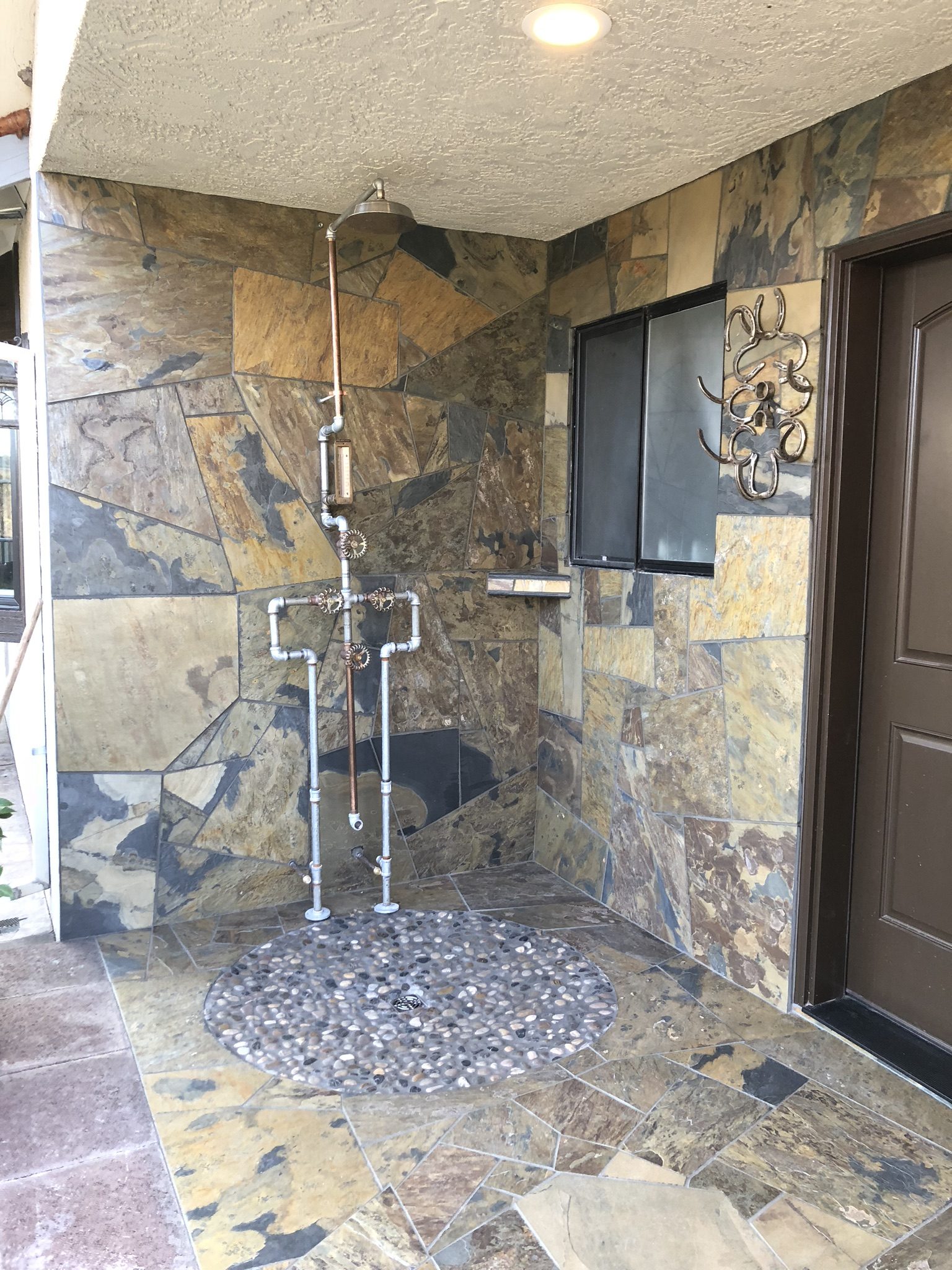 Custom outdoor shower with slate tile walls and river-pebble floor